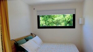 Una piccola camera con un letto singolo e una finestra che si affaccia sul verde.