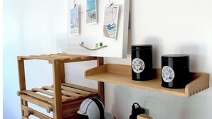 Una stanza con una scala di legno, una moka nera, un casco bianco e uno scaffale con delle foto.