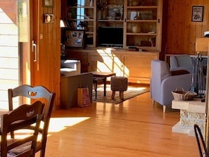 A cozy living room with wooden floors, a sofa, a chair, and a television.