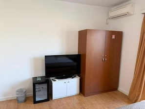 A room with a television, a cabinet, a trash bin, and an air conditioning unit. - Hotel Sidi (Tirana)