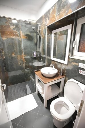 A bathroom with a glass-enclosed shower, a white sink, and a toilet. - Hotel Sidi (Tirana)