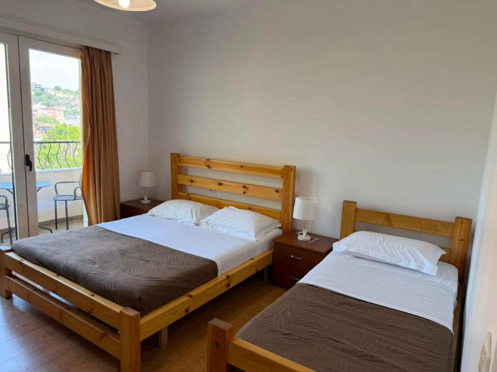 Una cama doble con estructura de madera, dos mesitas de noche con lámparas y vistas al exterior a través de una puerta corredera.