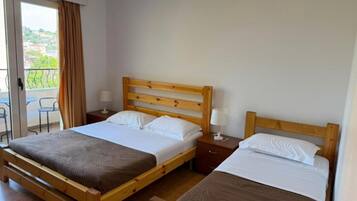 Una cama doble con estructura de madera, dos mesitas de noche con lámparas y vistas al exterior a través de una puerta corredera.