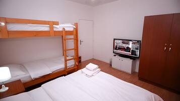 Quarto com beliches, televisão, guarda-roupa e secretária com candeeiro.