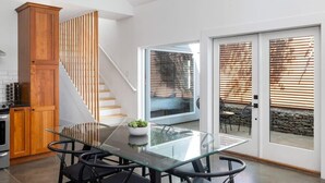 Eine moderne Küche mit einem Glastisch, Holzschränken und einer Treppe.
