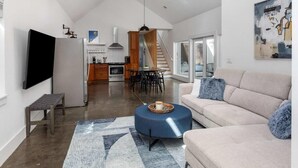Ein geräumiges Loft mit hohen Decken, einem Essbereich, einer Küche und einem Wohnzimmer mit Sofa und Hocker.