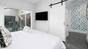 Ein Schlafzimmer mit einem Bett, einem an der Wand montierten Fernseher, einer Schiebetür und einer Wand mit Muster.