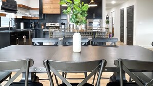 Una cucina moderna con mobili neri, elettrodomestici in acciaio inossidabile e una zona pranzo con un tavolo e sedie spaziosi.
