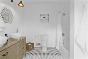 Un baño con un lavabo blanco, un tocador color beige, un inodoro, una ducha y un espejo en la pared.
