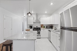 A modern kitchen with white cabinetry, stainless steel appliances, and a granite countertop.