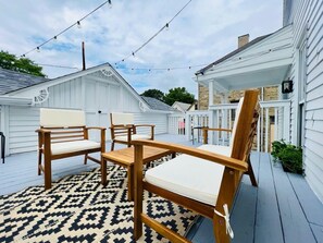 A wooden deck with a patterned rug, a table, and four chairs.