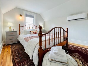 Quarto com cama de madeira, mesa de cabeceira, abajur e janela.