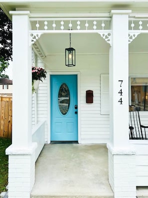 A white house with a blue door, a porch with white columns, and the number 744 on the right.