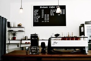 A coffee shop interior with a menu board, espresso machine, and a pickup order sign.
