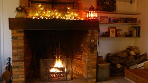 A brick fireplace with a fire, surrounded by shelves with books and decorative items. - Lyons-la-Forêt, charming Orfea's home, sleeps 8. Forest access, baby-friendly (Le Tronquay)