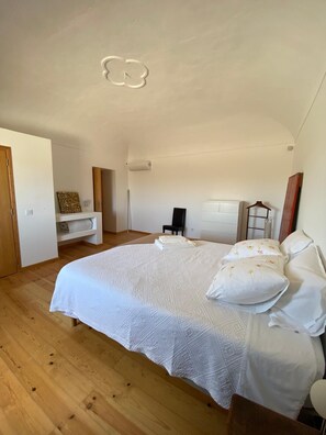 A bedroom with a large bed, a dresser, a chair, and a wardrobe.