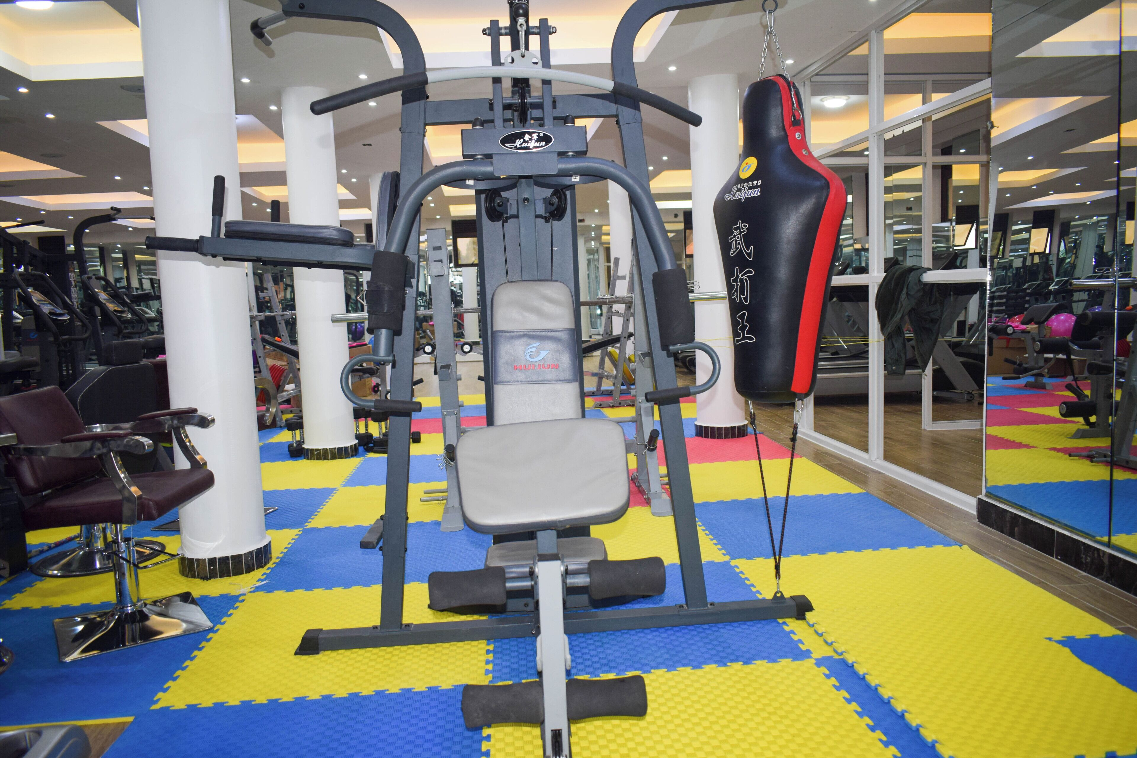 A gym with exercise equipment, a punching bag, and a mirrored wall.