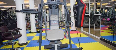 A gym with exercise equipment, a punching bag, and a mirrored wall.