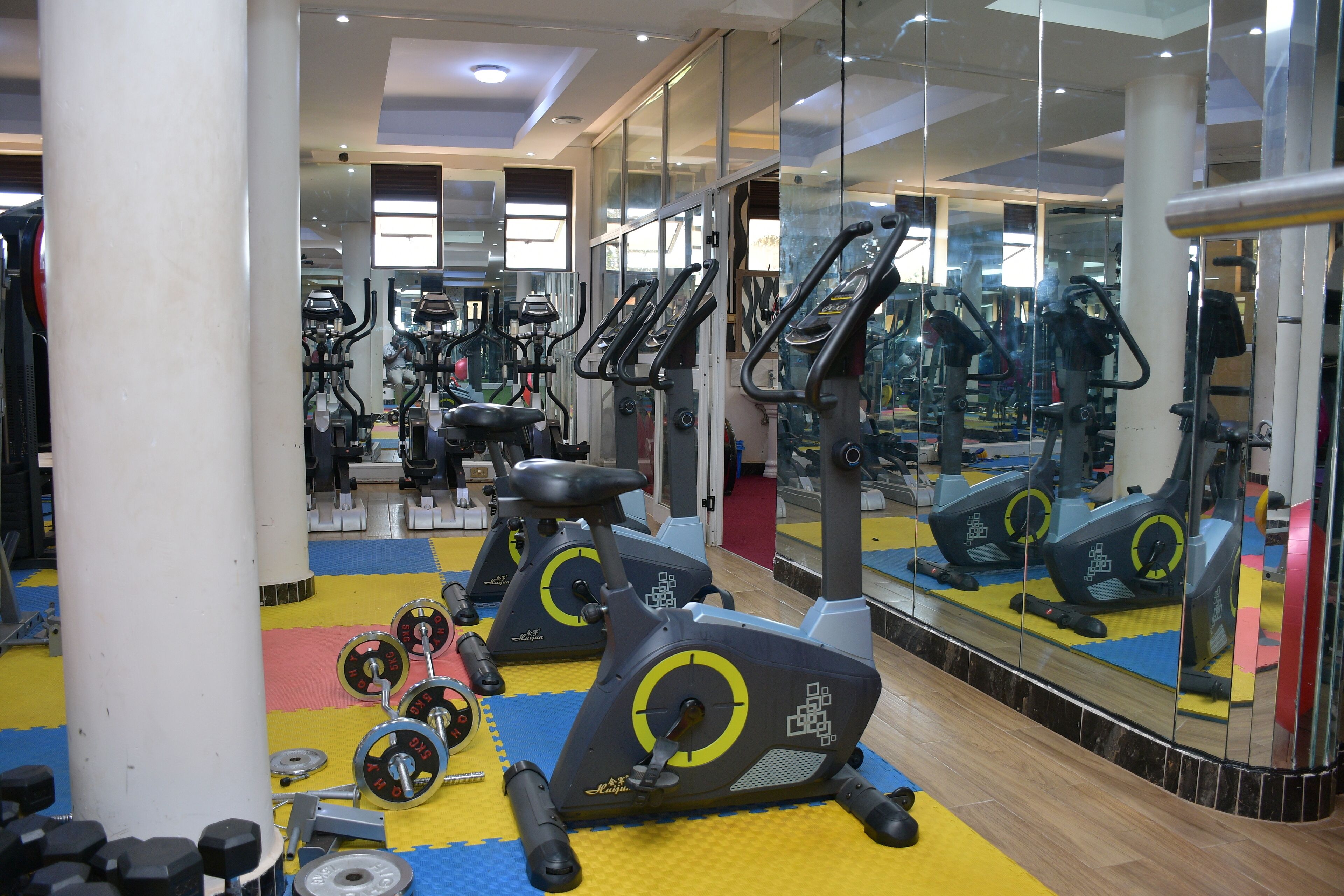 A gym with exercise equipment, mirrors, and a colorful floor.