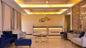A spacious lobby with modern furniture, a reception desk, and a decorative partition.