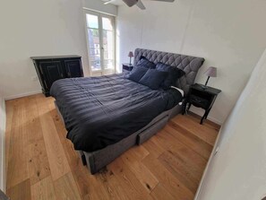 Une chambre à coucher avec un grand lit, une table de chevet, une commode et une fenêtre donnant sur un beau paysage.