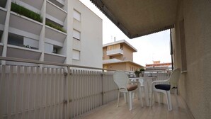 A balcony with a white railing, two white chairs, and a small table.