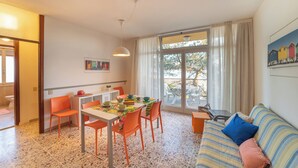 A dining area with a table and chairs, a sofa, and a window with curtains.