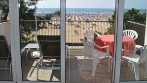 A balcony with a view of a crowded beach and the sea.
