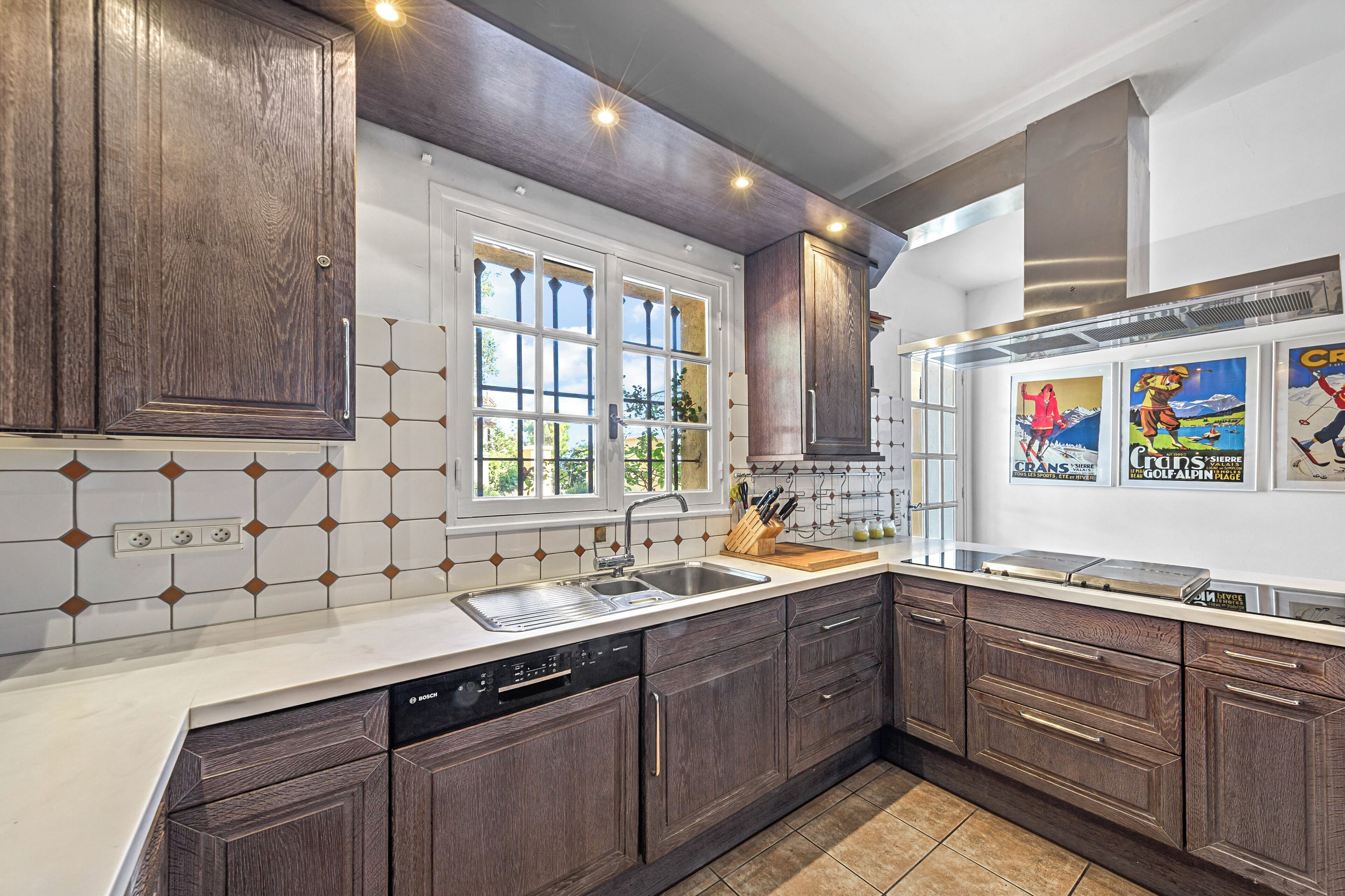 A modern kitchen with wooden cabinets, a built-in dishwasher, and a large window.