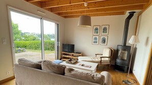 A cozy living room with a sofa, a television, a fireplace, and a sliding glass door leading to a deck.