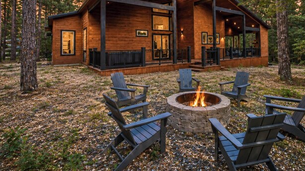 A cabin with a fire pit and four Adirondack chairs in front. - Pet-Friendly Forest Retreat for Families & Friends (Broken Bow)