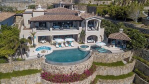 Une grande maison à plusieurs étages, dotée d’une piscine, d’un espace extérieur aménagé et d’un mur de soutènement en pierre.