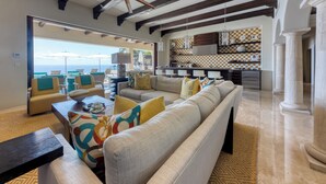 Un vaste espace de vie comprenant un grand canapé, une table basse et une vue sur la mer.