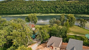 Una propiedad frente al lago con una casa, un muelle y vistas al lago y colinas boscosas.