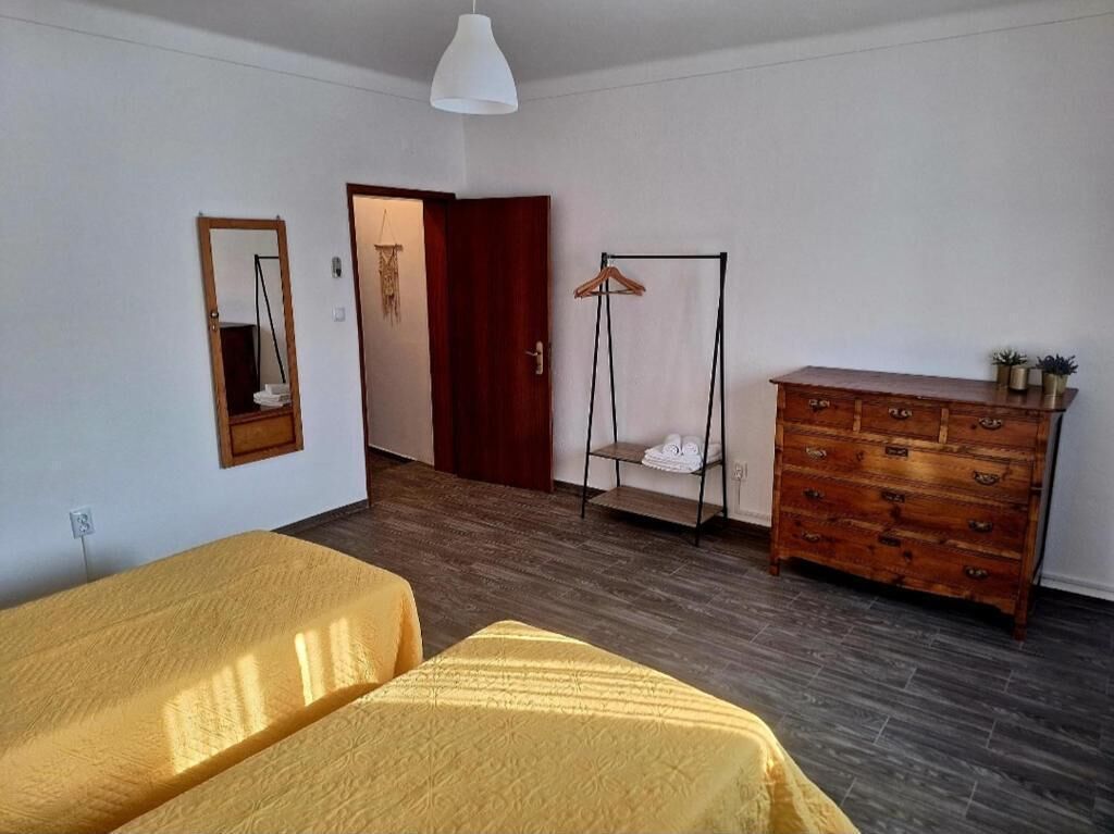 Una habitación con dos camas, un aparador de madera, un perchero y un espejo en la pared.