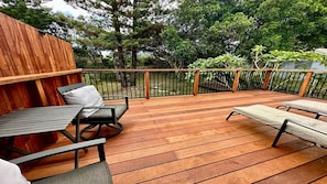 An outdoor deck with wooden flooring, metal railings, and outdoor furniture including a table and chairs. - Wooli Waves - Right on the ocean dune. (Wooli)