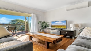 A modern living room with a wooden coffee table, a television, and a sofa.