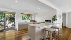 Une cuisine moderne dotée d’un îlot central, de planchers en bois et offrant une vue sur l’extérieur.