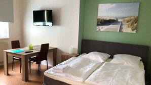 Et hotelværelse med en seng, et skrivebord og et fjernsyn.