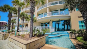 A multi-story hotel with balconies, a swimming pool, and palm trees. - Aqua 802 Oceanfront/Hi+Clean Standard/Wifi/Beach Chairs (Panama City Beach)