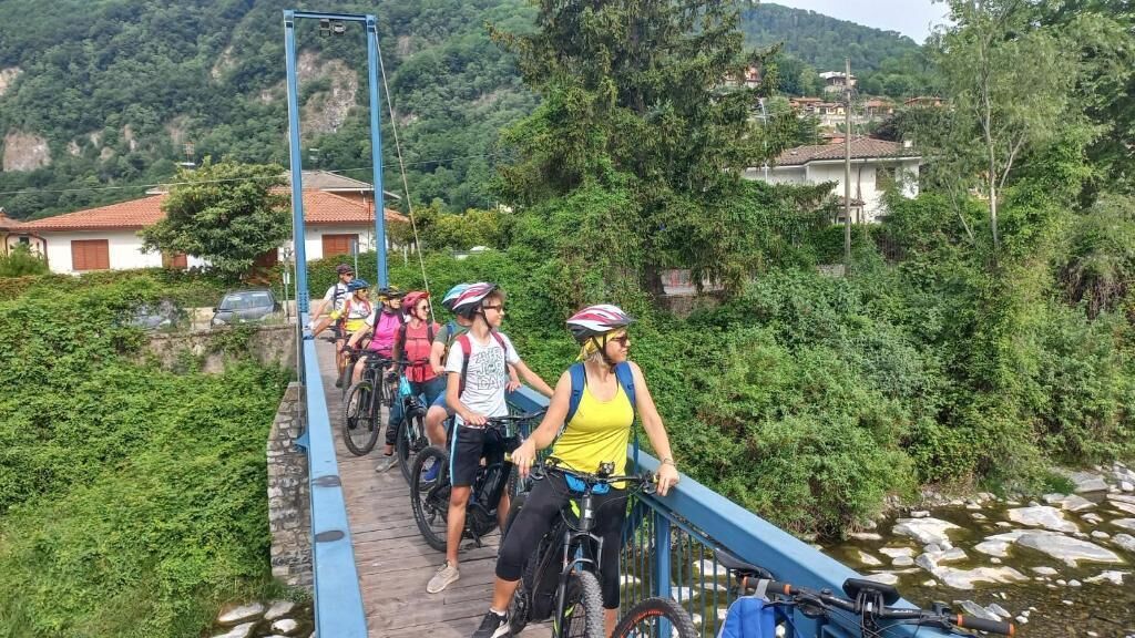 A group of cyclists on a bridge with a rural backdrop.