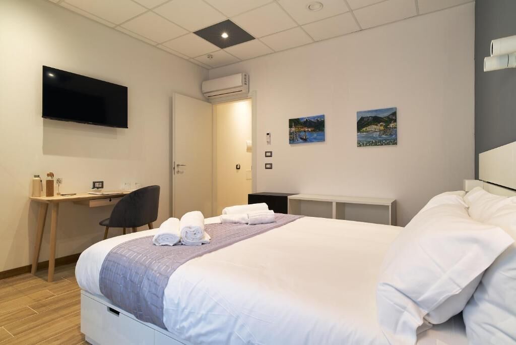 Ein Hotelzimmer mit Bett, Schreibtisch, Stuhl, Fernseher und zwei Bildern an der Wand.