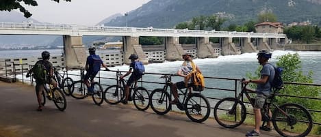 Un grupo de ciclistas sobre un puente, con un río y montañas al fondo.