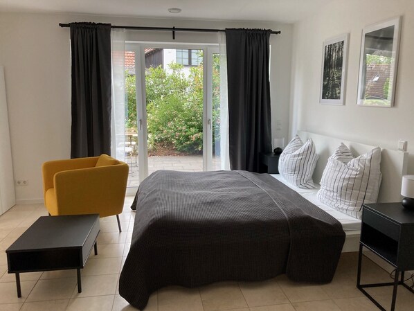 A bedroom with a bed, a yellow chair, a small table, and a desk. - 1-Bedroom Apartment in Solingen (Solingen)