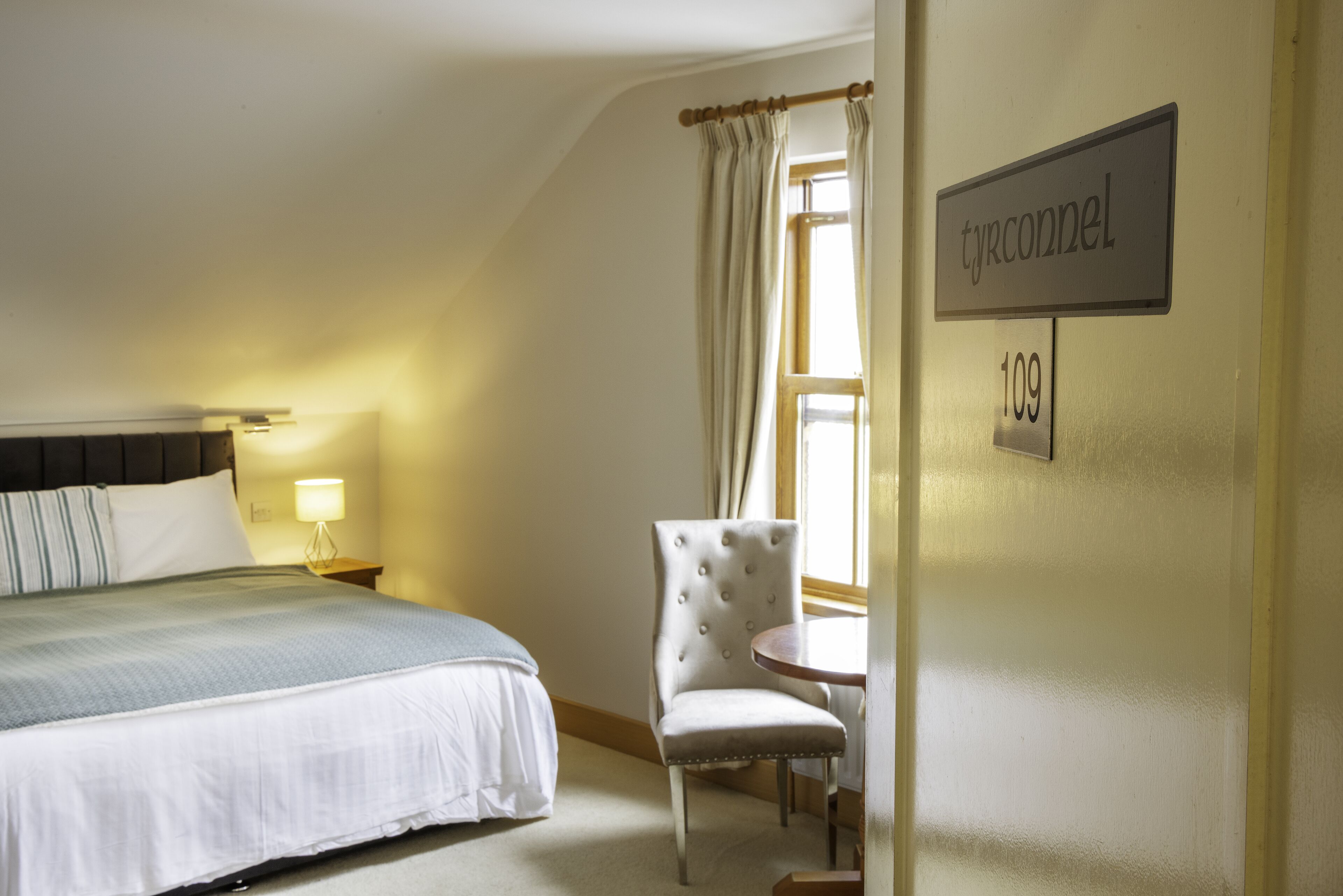 Een hotelkamer met een bed, een stoel, een klein tafeltje en een bordje met het nummer 109.