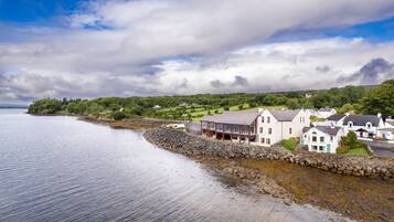 A coastal town with houses along the shore, a stone wall, and a clear view of the sea.