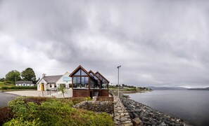 A coastal building with a stone wall and a view of the sea. - The Waters Edge (Rathmullan)