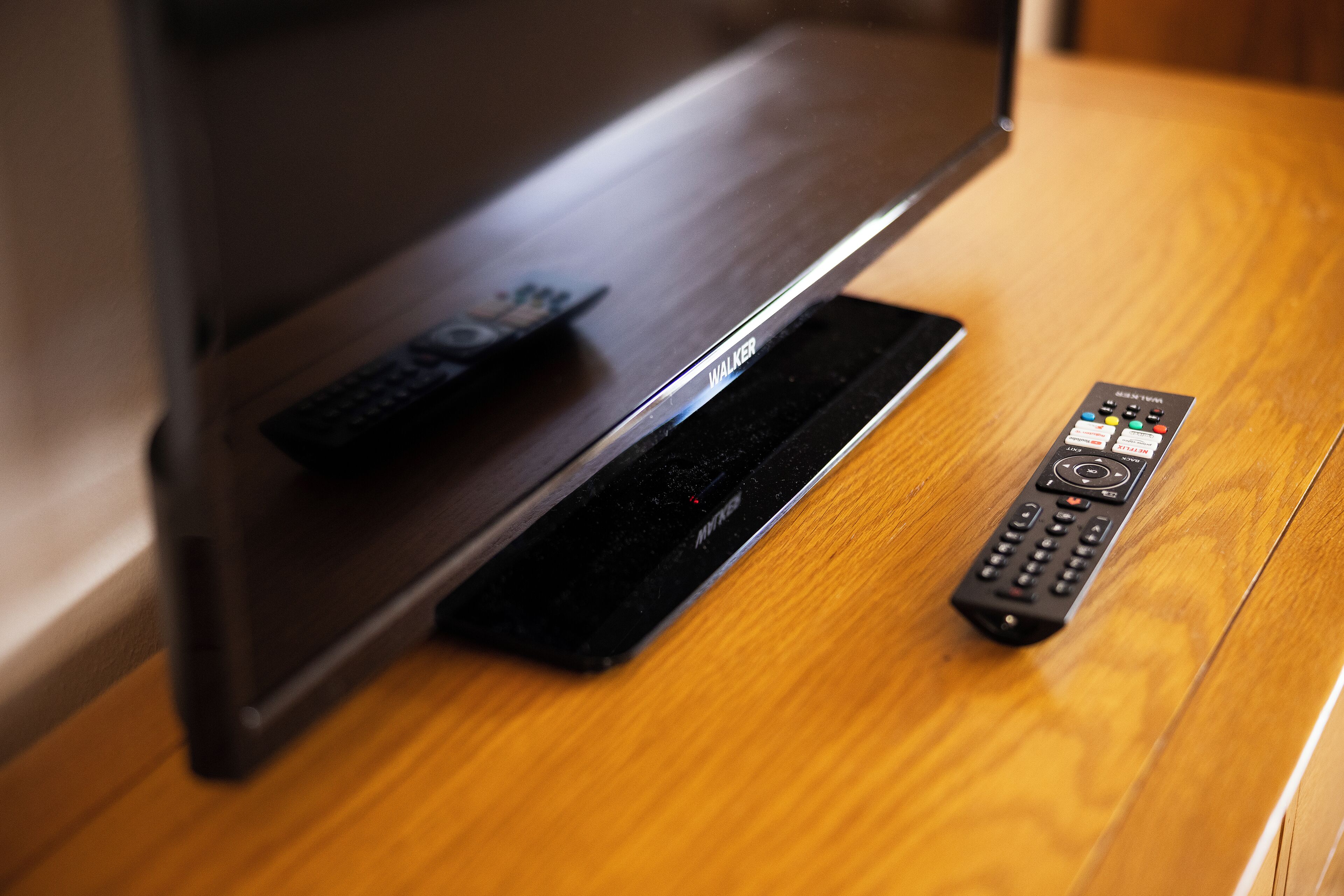 Une table en bois avec un meuble pour la télévision et deux télécommandes.