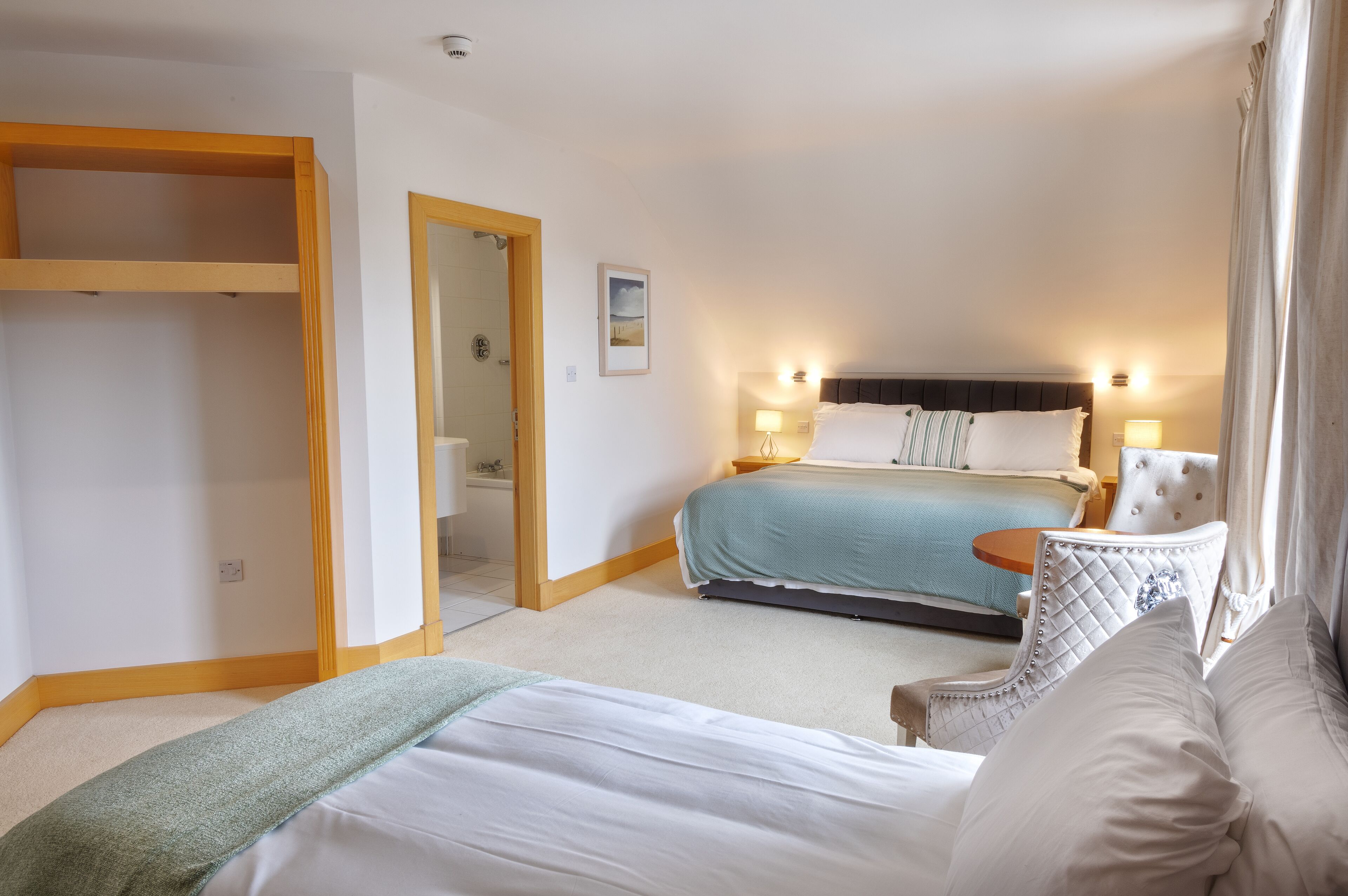 Een hotelkamer met een bed, een stoel, een nachtkastje en een kledingkast.