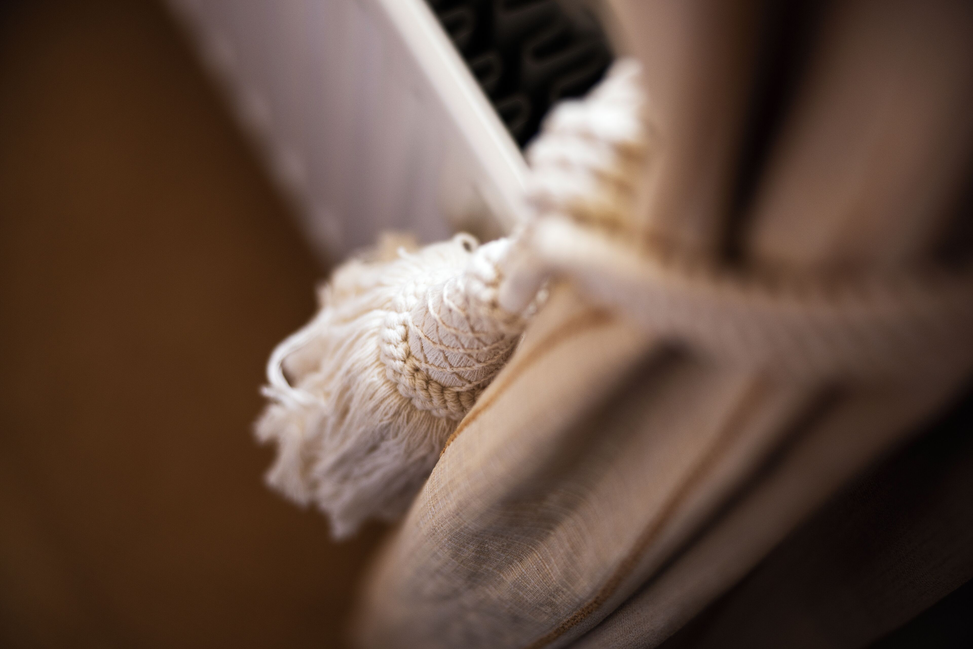 A close-up of a textured fabric, possibly a cushion or upholstery, with a frayed edge.